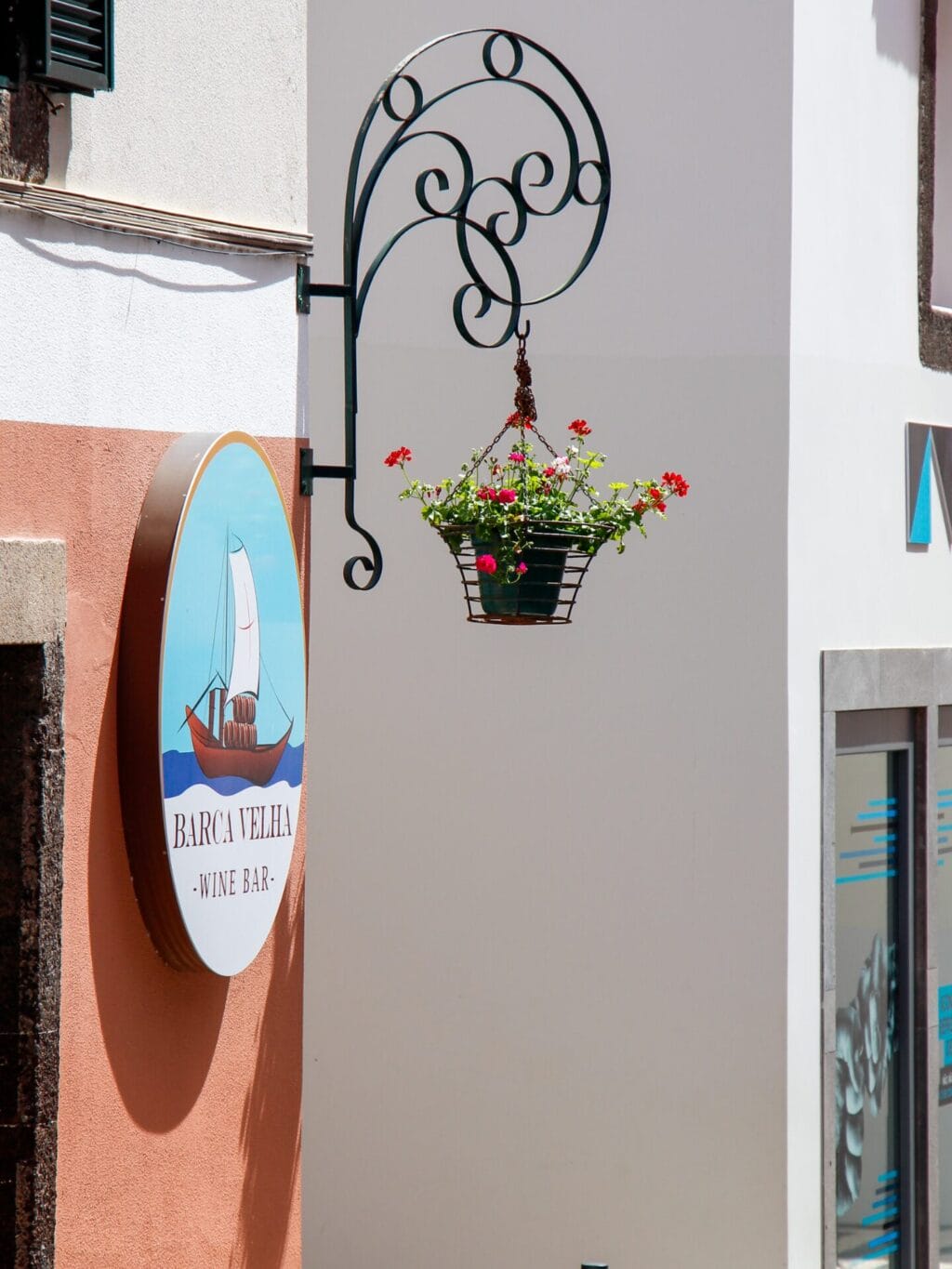 Eine Hausmauer, an welcher ein Restaurantschild sowie ein Blumentopf hängen